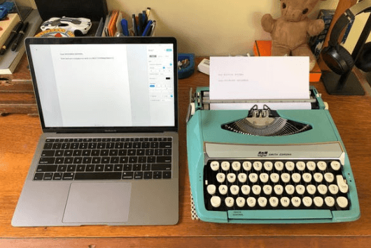 Photo of a Macbook next to an old typewriter
